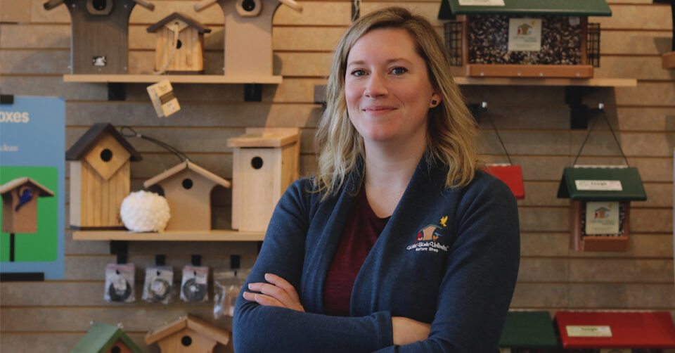 Wild Birds Franchise Owner Sarah Smith poses in front of birdhouses.