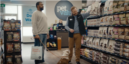 Pet Valu: an employee displays merchandise to a searching customer.