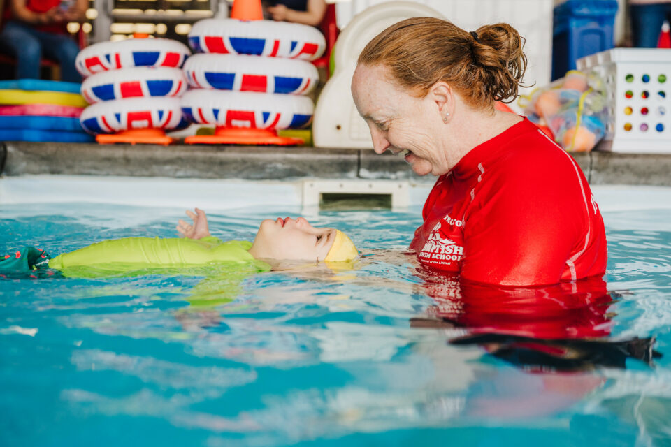 British Swim School Franchise image: A swim instructor holds a baby on the surface of the water.