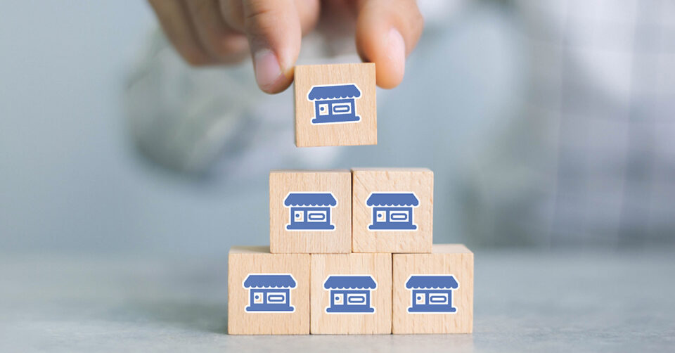 Person stacking wooden blocks with blue storefront icons on them