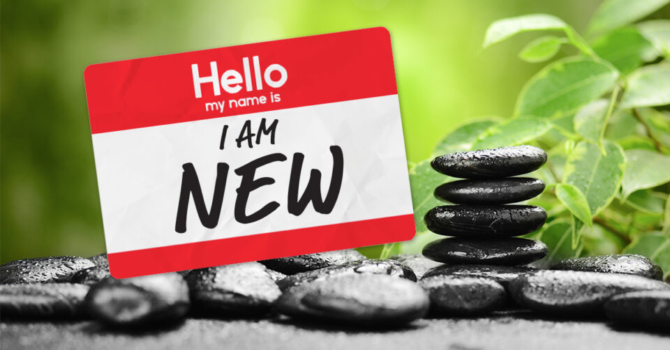 Nametag saying "Hello I am New" on a wellness inspired background of stacked rocks and leaves